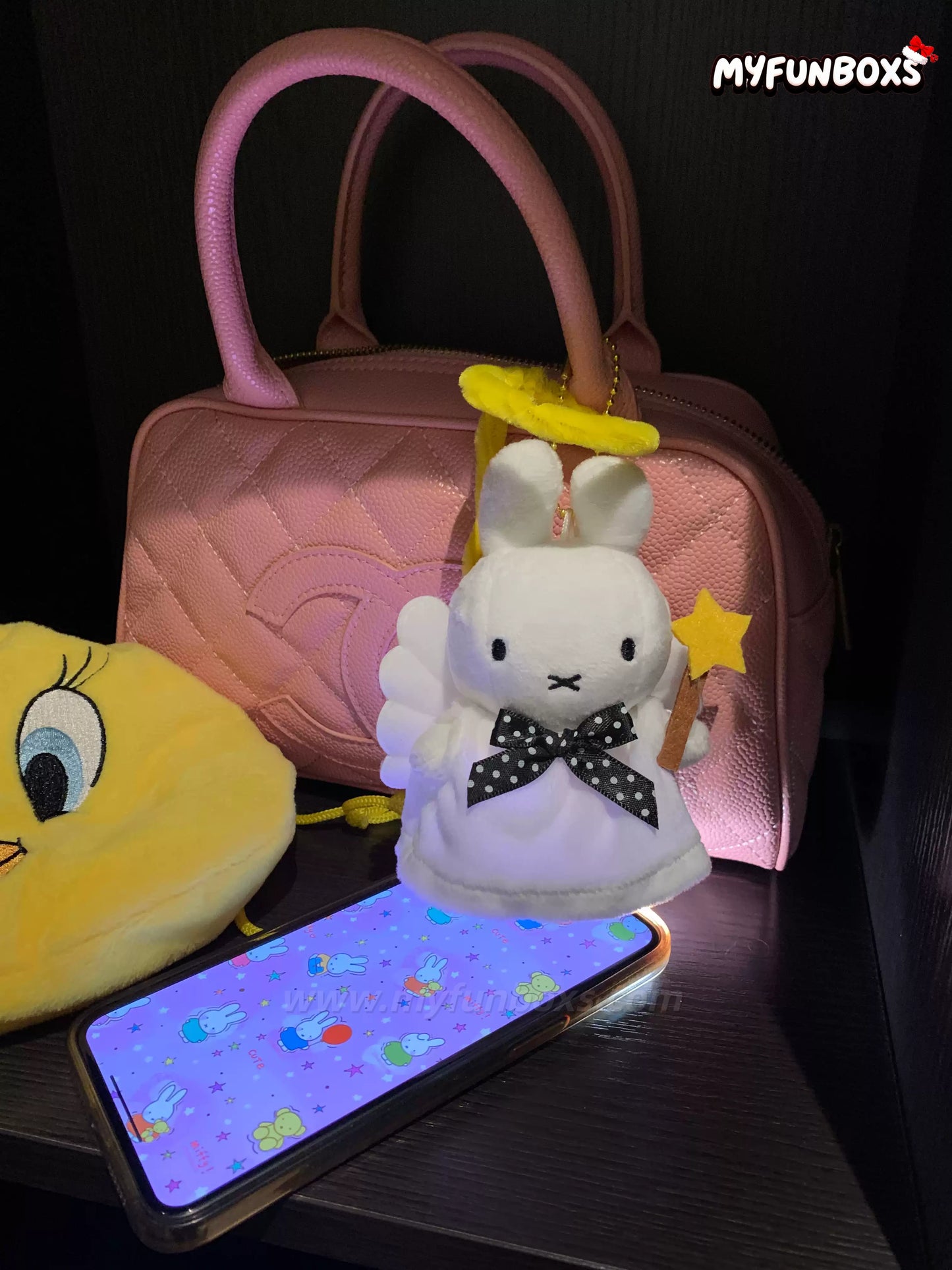 Angel Miffy bag charm next to pink handbag and Miffy-themed phone