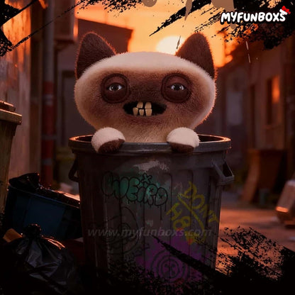 Brown and white fuzzy cat plush doll peeking out of graffiti-covered trash bin at sunset